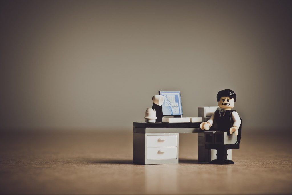 lego person figurine sitting at a desk with a frustrated look on its face